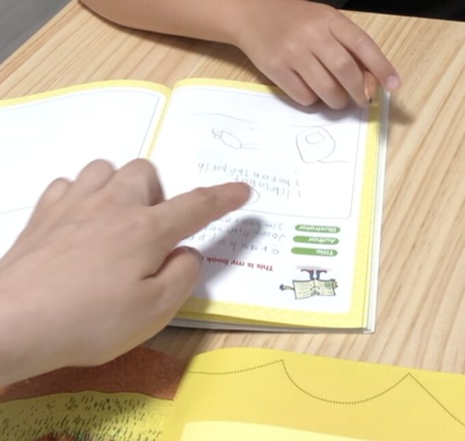 小学生に英語で記録の指導をする様子