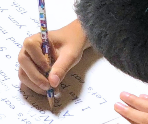 英語の文章を手書きする男の子画像